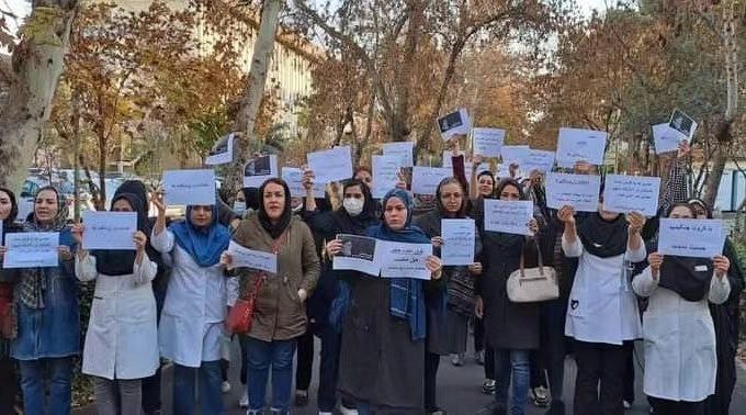چند ده زن پلاکاردهای اعتراضی در دست دارند