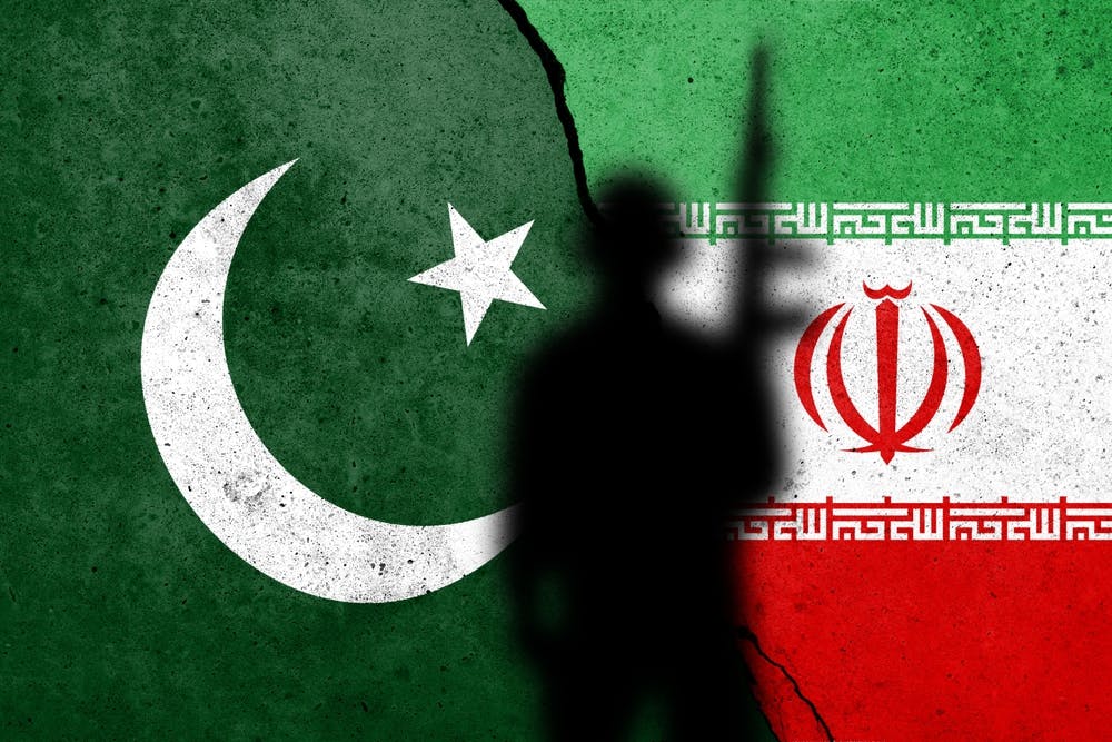 پرچم ایران و پاکستان، سایه یک مرد سرباز میان دو پرچم دیده می‌شود - طرح از شاتراستاک