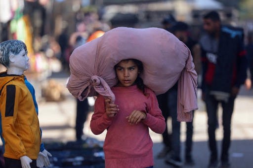 یک دختر فلسطینی با لباس صورتی و یک گونی صورتی رنگ روی سرش. چهره‌اش مصمم و کمی مبهوت است.