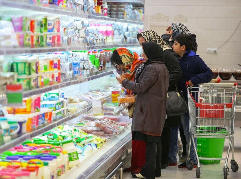چند زن و یک کودک با سبد خرید خالی در کنار قفسه گوشت و لبنیات به قیمت‌ها نگاه می‌کنند.