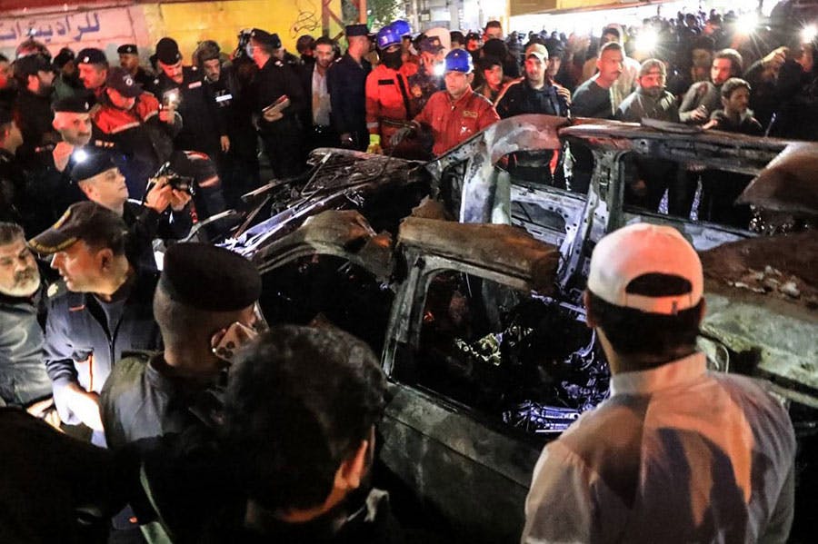 مردم، امدادگران و نیروهای امنیتی در اطراف خودرو منفجر شده رهبران گروه کتائب حزب‌الله عراق جمع شده‌اند و سوخته آن را تماشا می‌کنند.