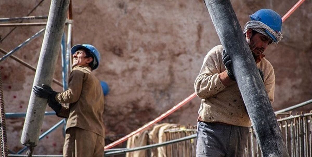 دو کارگر در پروژه نفت و گاز لوله‌های استوانه‌ای را بر سازه استوار می‌کنند.