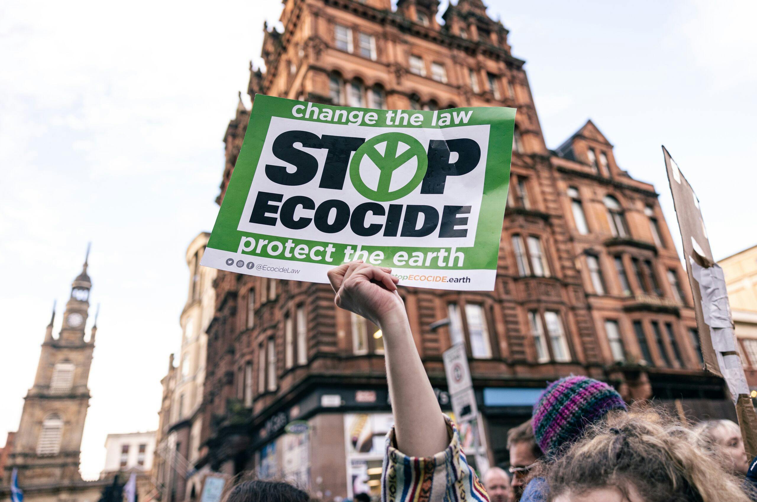 تصویر تزئینی از شاتر استاک یک نفر را در یک راهپیمایی محیط‌زیستی در اسکاتلند نشان می‌دهد که اعلانی در دست دارد که بر رویش نوشته شده «بوم‌کشی را متوقف کنید»