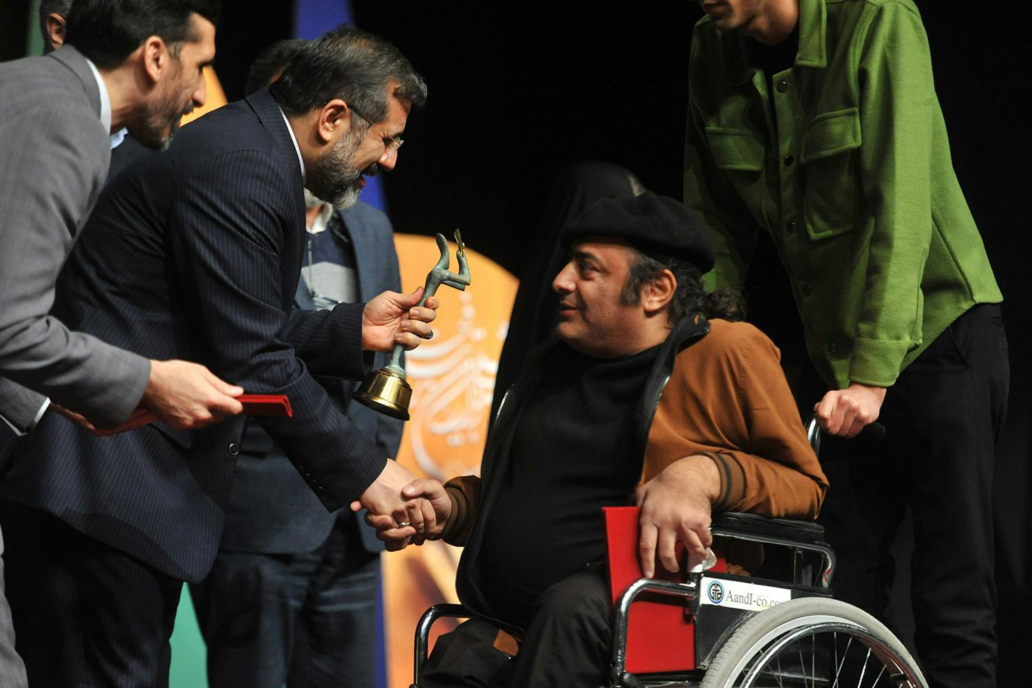 وزیر ارشاد در حال اهدای جایزه به یک هنرمند تئاتر دارای معلولیت در مراسم اختتامیه بخش فراگیر تئاتر فجر