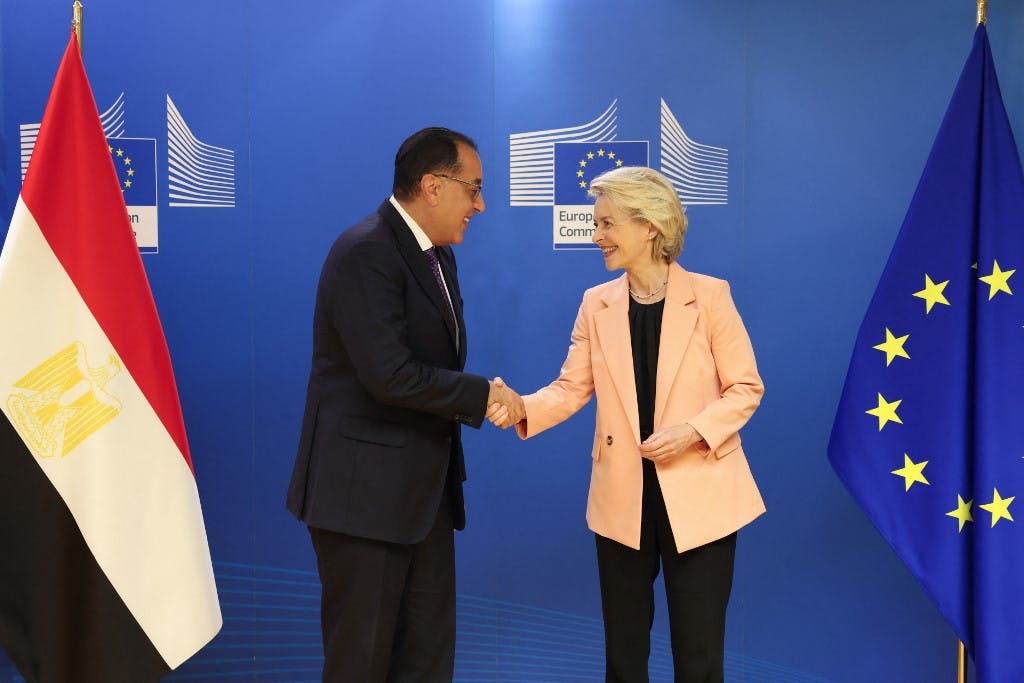 اورسولا فون در لاین، رئیس کمیسیون اروپا (سمت راست) در حال دست‌دادن با مصطفی مدبولی، نخست وزیر مصر دیده می‌شود. سمت راست تصویر پرچم آبی اتحادیه اروپا و سمت چپ پرچم قرمز، سفید و مشکی مصر قرار دارد. (عکس از سیمون ولفارت / خبرگزاری فرانسه)