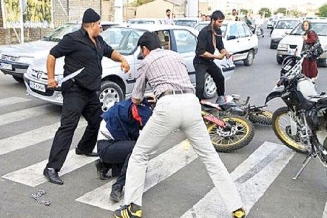 درگیری خیابانی در ایران: یک مرد قمه به دست بر روی خط عابر پیاده ایستاده است و دو شهروند با یکدیگر درگیر شده‌اند.