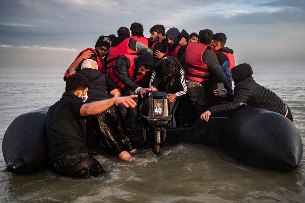 مهاجران پس از سوار شدن بر قایق قاچاقچی در ساحل Gravelines، در نزدیکی Dunkirk، شمال فرانسه در 12 اکتبر 2022، در تلاش برای عبور از کانال انگلیسی، سعی می کنند موتور بیرونی را روشن کنند.