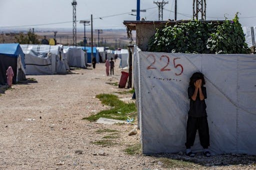 تصویری از ردیف چادرها در یک اردوگاه بازداشتگاهی به نام «روژ» در شمال شرق سوریه. جلوی نزدیکترین چادر به دوربین، یک دختربچه ایستاده و با دست‌هایش صورتش را پوشانده.