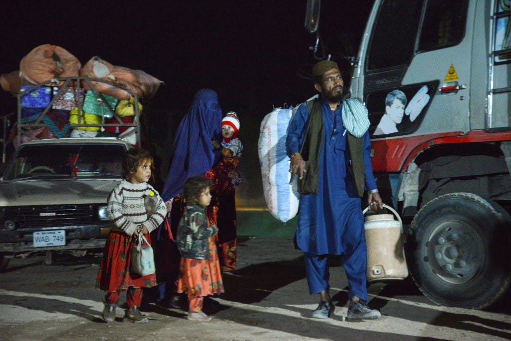 یک خانواده افغان (پدر و مادر و سه فرزند خردسال) در کنار وانت هایی مملوء از وسایل