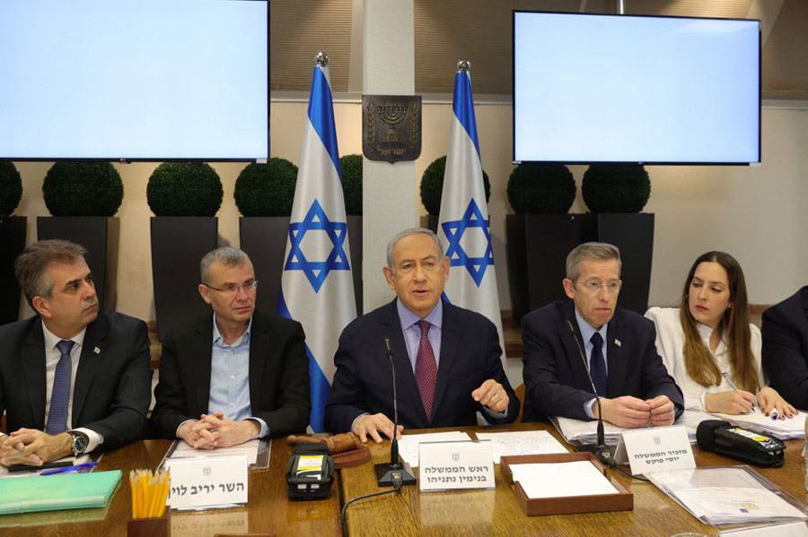 بنیامین نتانیاهو، نخست‌وزیر اسرائیل در نشست کابینه جنگی این کشور در حال سخنرانی است و اطراف او چند تن از وزیران نشسته‌اند.