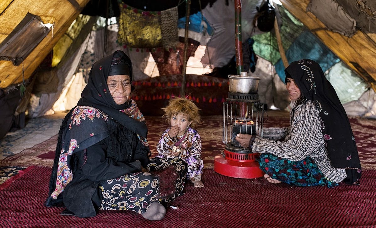 تصویری از داخل چادر کولی‌های تربت حیدریه. دو زن که در میان آن‌ها یک کودک نشسته است.