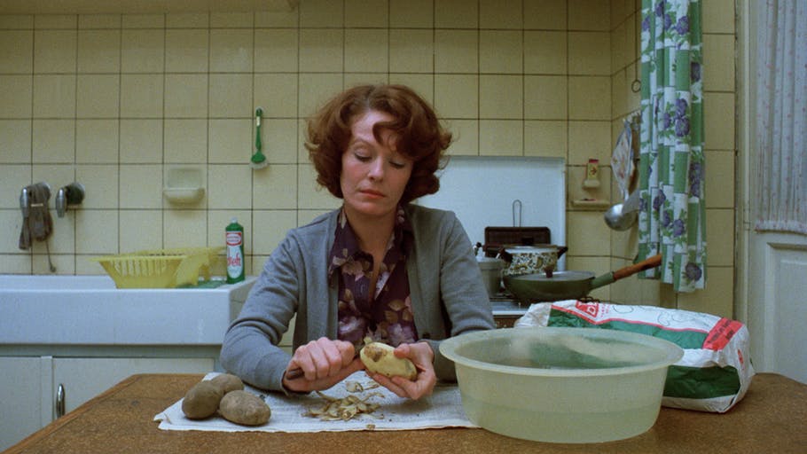 زنی در آشپزخانه در حال سیب زمینی پوست کندن
