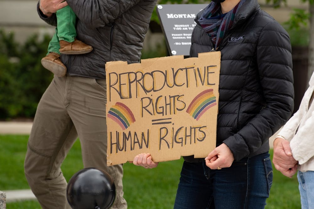 یک فرد که چهره‌اش پیدا نیست مقوایی دست گرفته که روی آن به انگلیسی نوشته: حقوق بازتولیدی = حقوق بشر. در دو طرف مقوا رنگین‌کمان کشیده شده است.