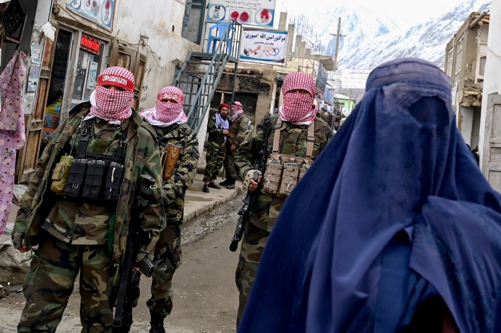 زنی با برقع و پشت سرش سخ عضو طالبان