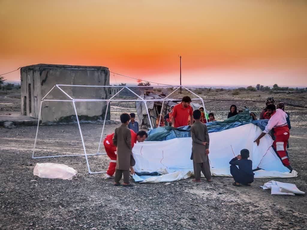 تصویر از هلال‌ احمر ایران که تلاش این سازمان برای برپایی چادر برای آوارگان اقلیمی در سیستان و بلوچستان را نشان می‌دهد.