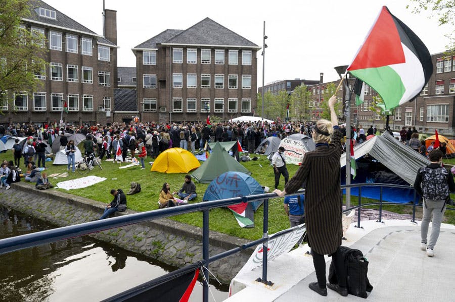 دانشجویان طرفدار فلسطین در محوطه دانشگاه آمستردام پرچم‌ها و پلاکاردهایی به دفاع از مردم فلسطین در دست دارند.