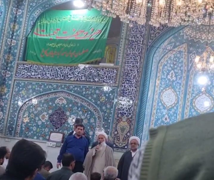 جلوی محراب مسجد حجت اصفهان دو روحانی و یک مرد با لباس آبی ایستاده‌اند. روحانی میکروفون به دست دارد و سخنرانی می‌کند