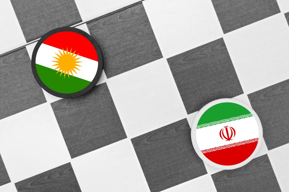 مهره به رنگ پرچم ایران و مهره‌ای به رنگ پرچم کردستان بر یک صفحه شطرنج
