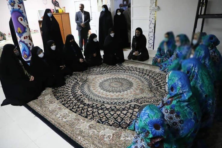 چند زندانی زن در برابر چند مسئول زن نشسته اند روی زمین