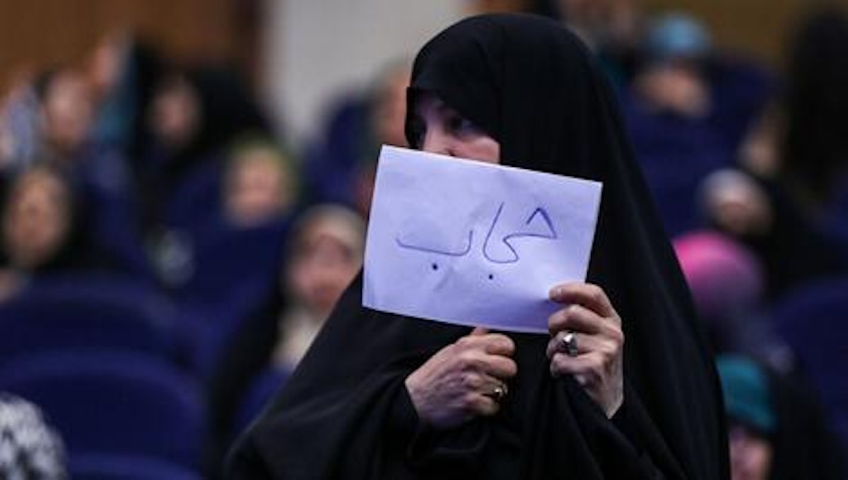 زنی چادر پوشیده روی کاغذ نوشته «حجاب» و آن را جلوی صورتش گرفته