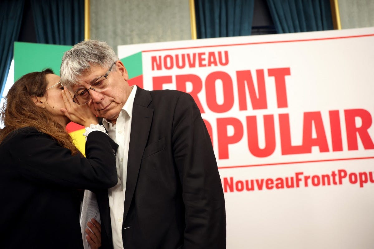 اریک کوکرل، از حزب فرانسه‌ی تسلیم‌ناپذیر، در سمت راست، در حال گوش‌دادن به هم‌حزبی‌اش کلمنس گت در سمت چپ، در جریان کنفرانس خبری اعلام هزینه‌های تخمینی برنامه‌ی انتخاباتی «جبهه‌ی مردمی جدید». پشت سرشان یک تابلوی سفید است که روی آن به قرمز و به زبان فرانسوی نوشته جبهه‌ی مردمی جدید