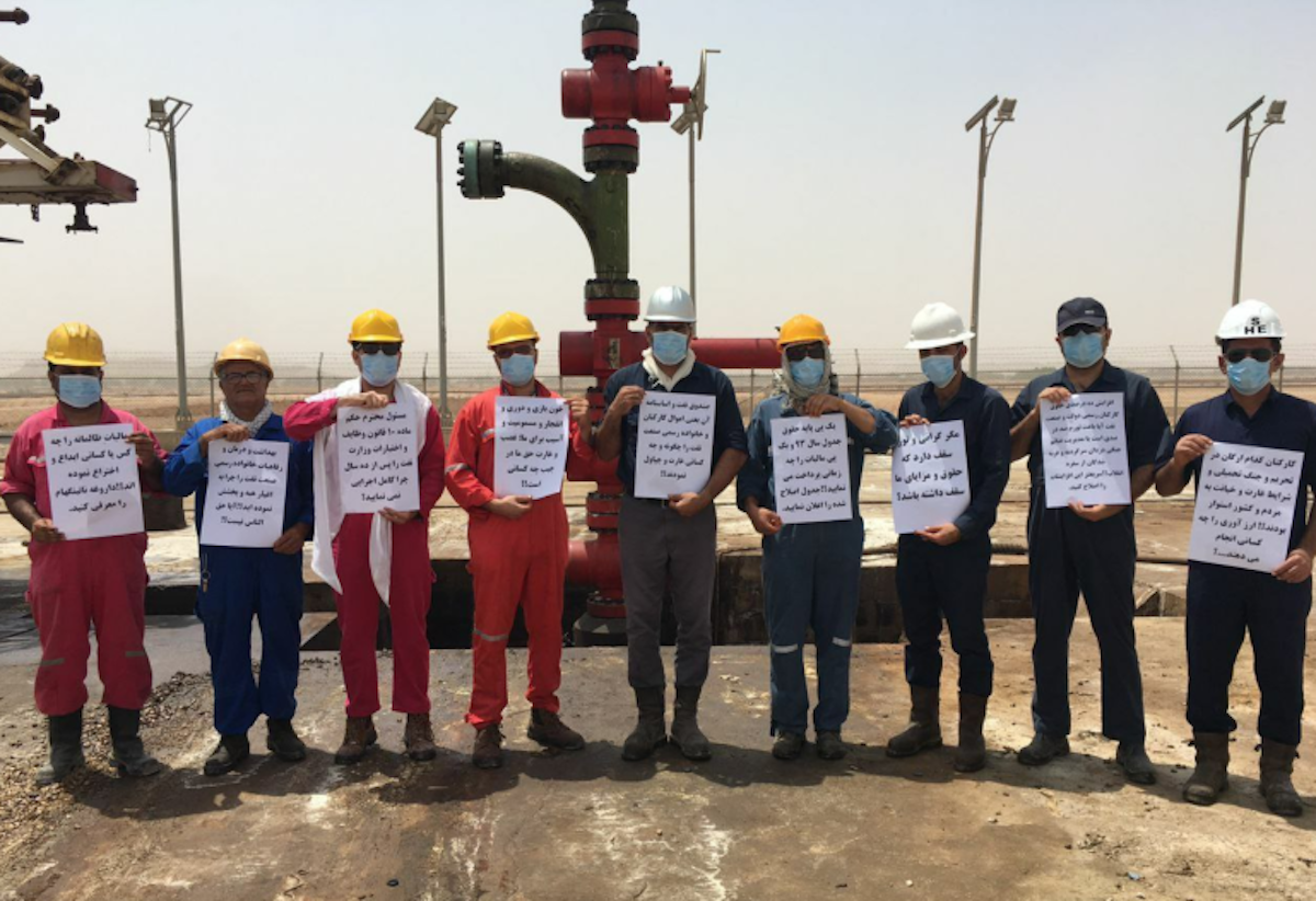 کارگران نفت و گاز در حالی‌که ماسک‌هایی بر چهره دارند خواسته‌های خود را نوشته و در دست گرفته‌اند.