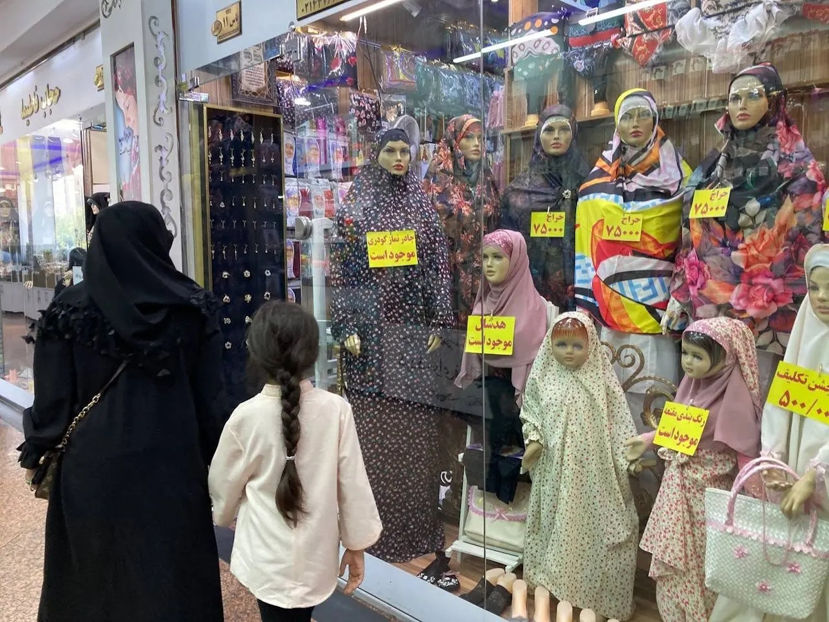 یک مادر و دختر از مقابل ویترین یک مغازه پر از لباس‌های اسلامی می‌گذرند