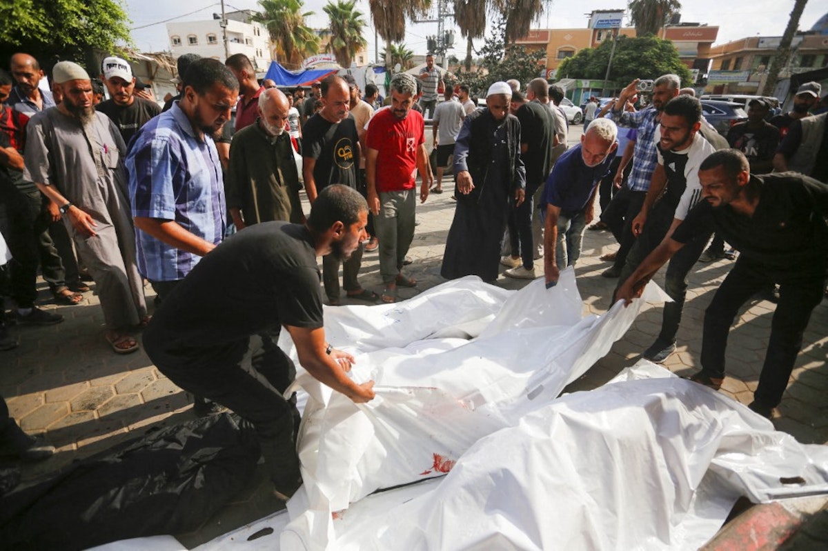 مردم اجساد فلسطینیانی را که در حمله اسرائیل به اردوگاه نصیرات کشته شدند، در سردخانه بیمارستان شهدای الاقصی قبل از دفن در دیرالبلاح، غزه در 17 ژوئیه 2024 حمل می کنند.