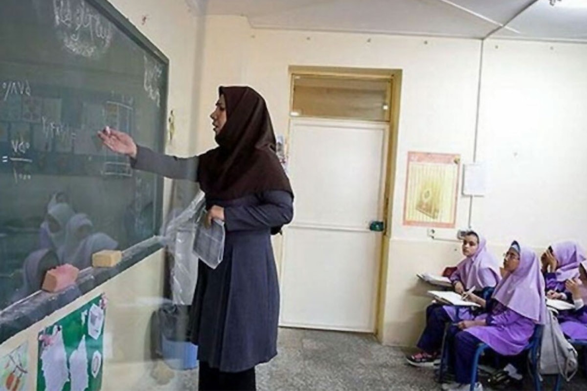 یک معلم زن پای تخته‌سیاه به دانش‌آموزان درس می‌دهد.