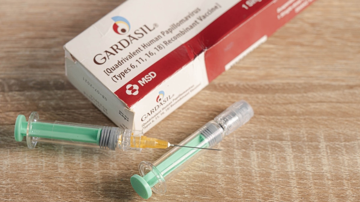 سوزن تزریق و جعبه واکسن "GARDASIL" روی پس زمینه قرار داده شده است.